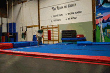 the rules of circus are written on a wall above a trampoline