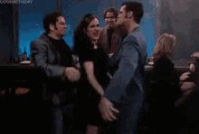 a group of people are dancing in a club while a man looks on .