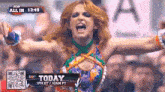 a female wrestler is screaming with her arms outstretched in front of a crowd at a wrestling event