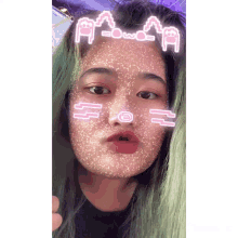a girl with green hair is wearing a mask with a cat face and the letters a and w on her forehead