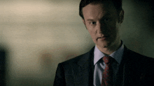 a man in a suit and tie looks to the side