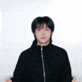 a young man wearing a black jacket is making a funny face