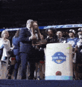 a man holding a trophy in front of a barrel that says final four on it