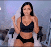 a woman in a black bra and shorts is sitting in a chair with her hands in the air .