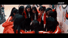 a group of girls huddled together with the word fever on the bottom right