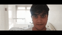a young man in a white shirt looks at the camera
