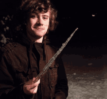 a young man in a brown jacket is holding a piece of ice in his hand
