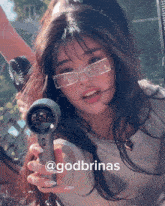 a girl wearing glasses is holding a hair dryer and has the name godbrinas on the bottom