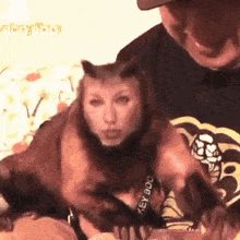 a man is holding a cat that is wearing a key dog bracelet