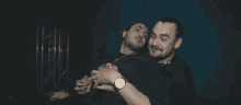 two men are hugging each other and one has a watch on