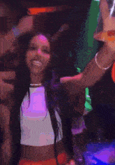 a woman is dancing in a club with a crowd of people behind her .