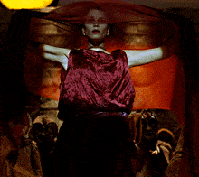 a woman in a red dress stands in front of a group of masks
