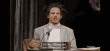 a man in a suit and bow tie is speaking into a microphone and says it 's like bleep shit