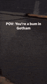 a man in a batman costume is standing in a parking lot at night