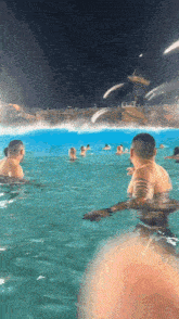 a group of men are swimming in a large pool at night