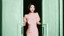 a woman in a pink dress is dancing in a doorway .