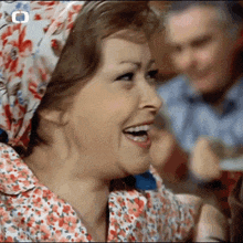a woman wearing a head scarf is laughing with a man in the background .