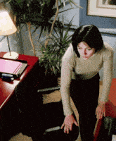 a woman in a tan sweater is standing next to a desk
