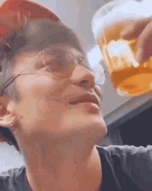 a man wearing sunglasses is holding a glass of beer in his hand .