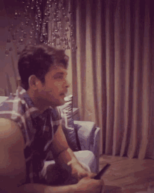 a man in a plaid shirt sits in a chair
