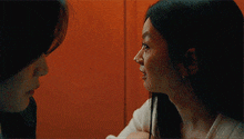 two women are looking at each other in an elevator and smiling .
