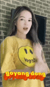 a woman wearing a yellow shirt with a smiley face on it