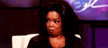 oprah winfrey is sitting in a chair and looking at the camera