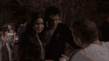 a man and a woman are standing next to each other in front of a crowd of people .