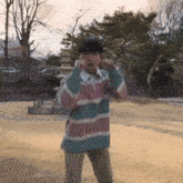 a man wearing a striped shirt is standing in a park