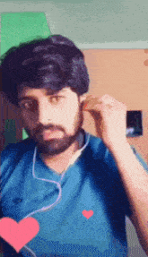a man with a beard wearing ear buds and a blue shirt