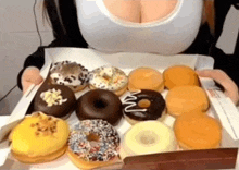 a woman is holding a box of donuts including a chocolate donut