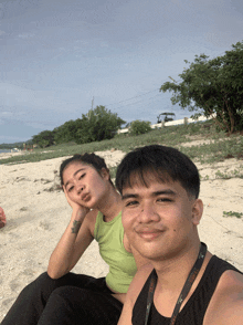 a man and a woman are sitting on the beach and the man is wearing a lanyard that says ' tsc '