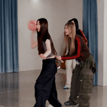 a group of young women are playing with a pink pillow