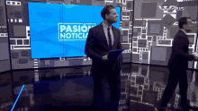 a man in a suit and tie is standing in front of a screen that says pasion noticia