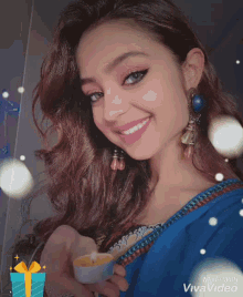 a woman in a blue dress is smiling and holding a candle in her hand .