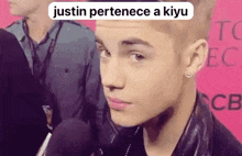 justin bieber is talking into a microphone while wearing a leather jacket and earrings .