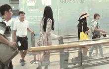 a group of people are standing in front of a glass wall that says gate 5-132