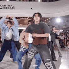a group of young men dancing in front of a sign that says central westgate