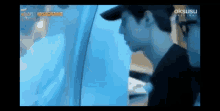 a man wearing a hat is standing next to another man in a blue room .