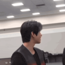 a man in a black jacket is standing in a room with ceiling lights .