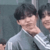 a man is making a funny face while another man holds his face .