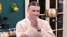 a man in a sweater is covering his mouth with his hands in front of a microphone with the word star academy on it