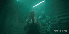 a woman is standing next to a man in a dark room with gifrun.com written in the corner