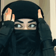 a woman wearing a black beanie and a black mask covering her face
