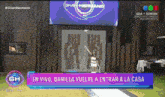 a woman stands in front of a sign that says gran hermano on it