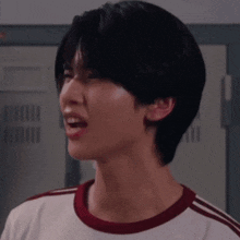 a man with short black hair is wearing a white shirt with red stripes on the sleeves