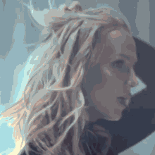 a woman with long blonde hair is standing in front of a window with her hand in her hair .
