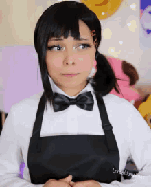 a woman wearing an apron and a bow tie has lordofdumplings written on her chest