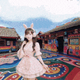 a girl wearing a pink dress and bunny ears stands in front of a colorful building