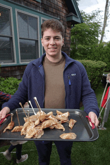 a man wearing a blue patagonia jacket holds a tray of food